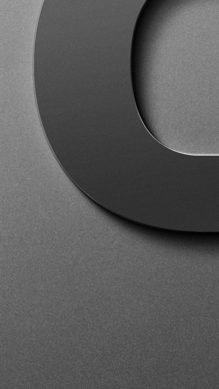 Abstrakte Nahaufnahme einer dunklen, abgerundeten Form auf grauer, strukturierter Oberfläche